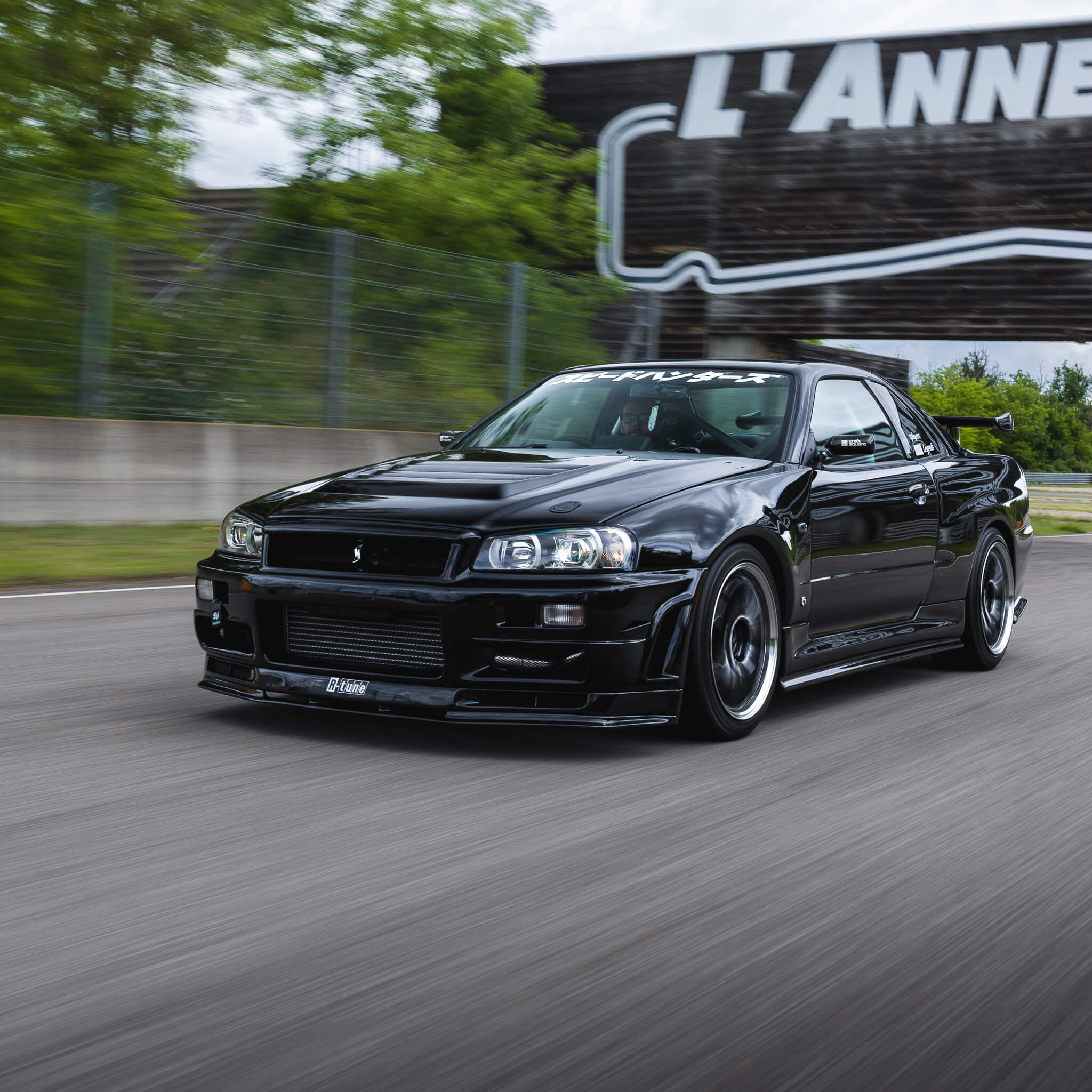 A dynamic driving shot of a black Nissan Skyline R34 on the race track